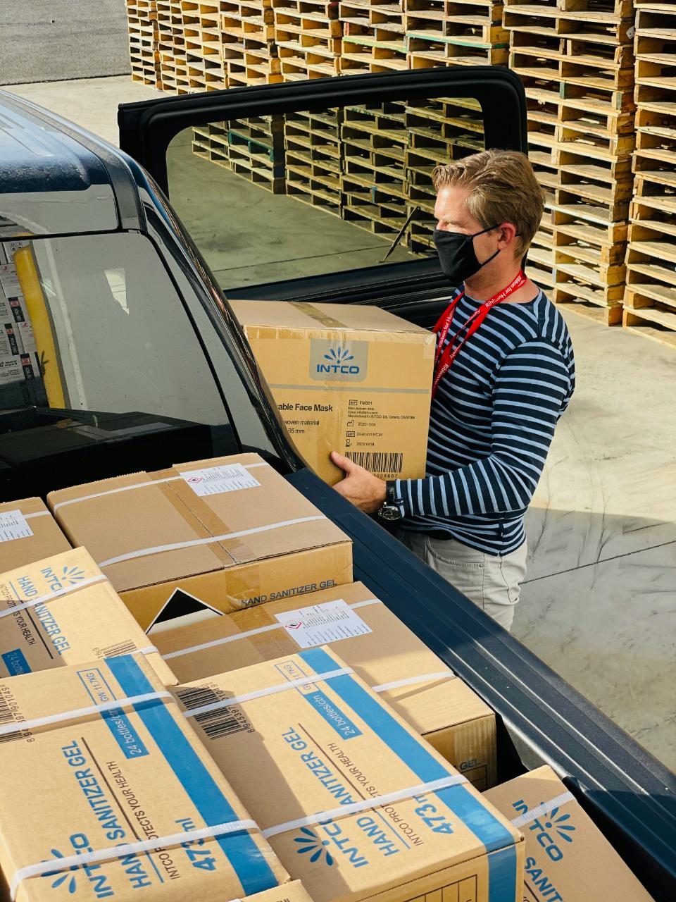 Worker loading hand sanitizer boxes into vehicle.