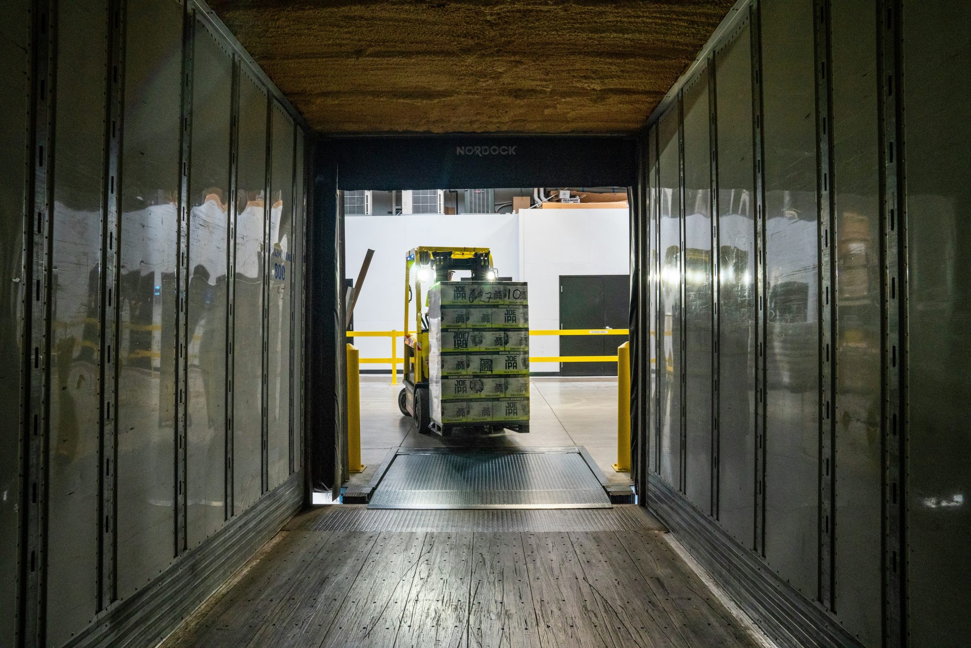 Forklift transporting goods inside a large delivery truck.