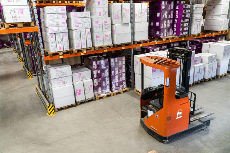 Forklift operating in a warehouse filled with organized inventory.