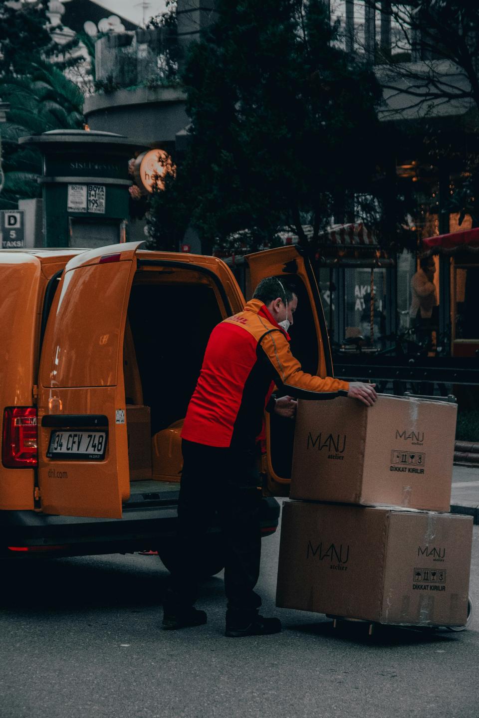 Courier unloading large packages from yellow delivery van