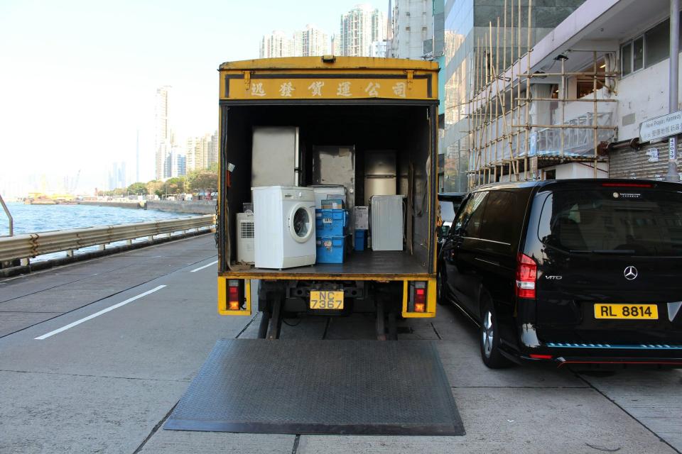 Moving truck transporting household appliances in urban area.